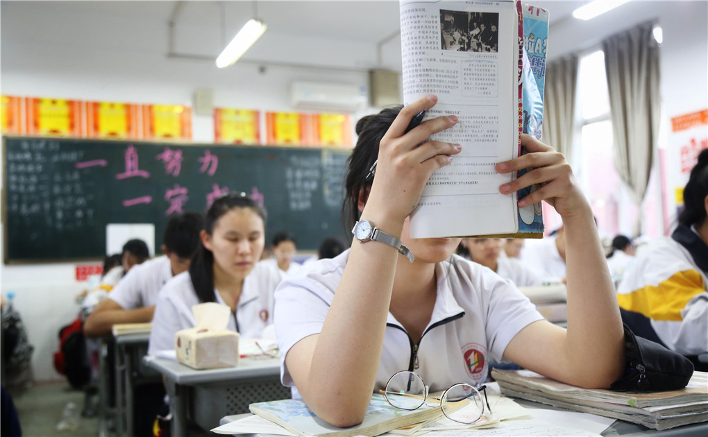 1.5月22日19时许，在淄博市第十一中学高三年级一文科班，一名学生正举起书本背诵。.jpg