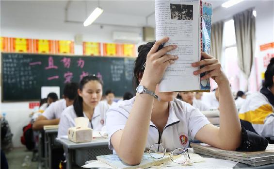 1.5月22日19时许，在淄博市第十一中学高三年级一文科班，一名学生正举起书本背诵。.jpg